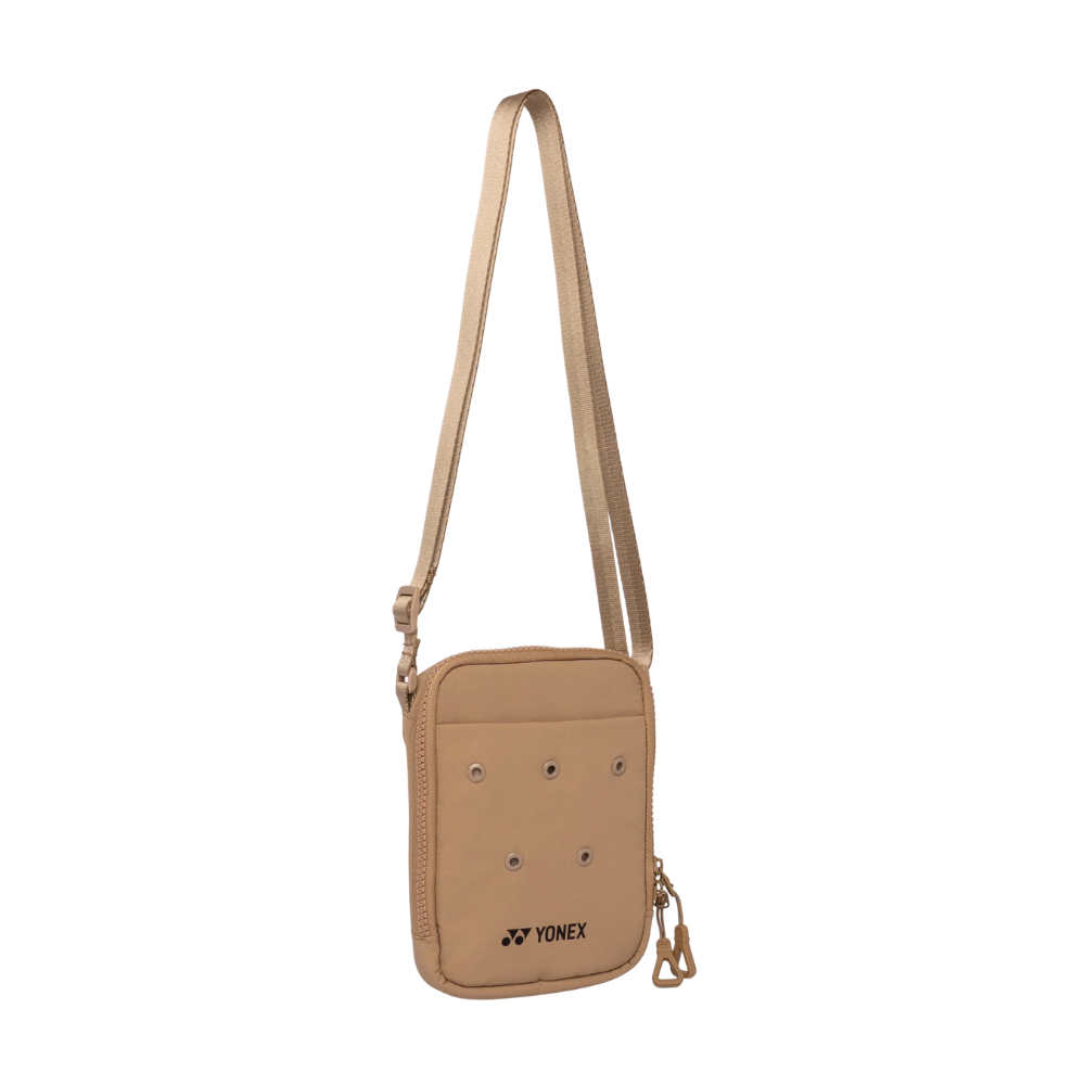 A tan Yonex crossbody bag with a matching adjustable shoulder strap, featuring a front zippered pocket with ventilation holes and the Yonex logo.